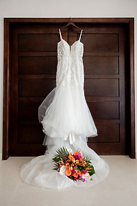 Wedding dress for April and Javiert on a hanger, with a vibrant bouquet below, ready for destination wedding.