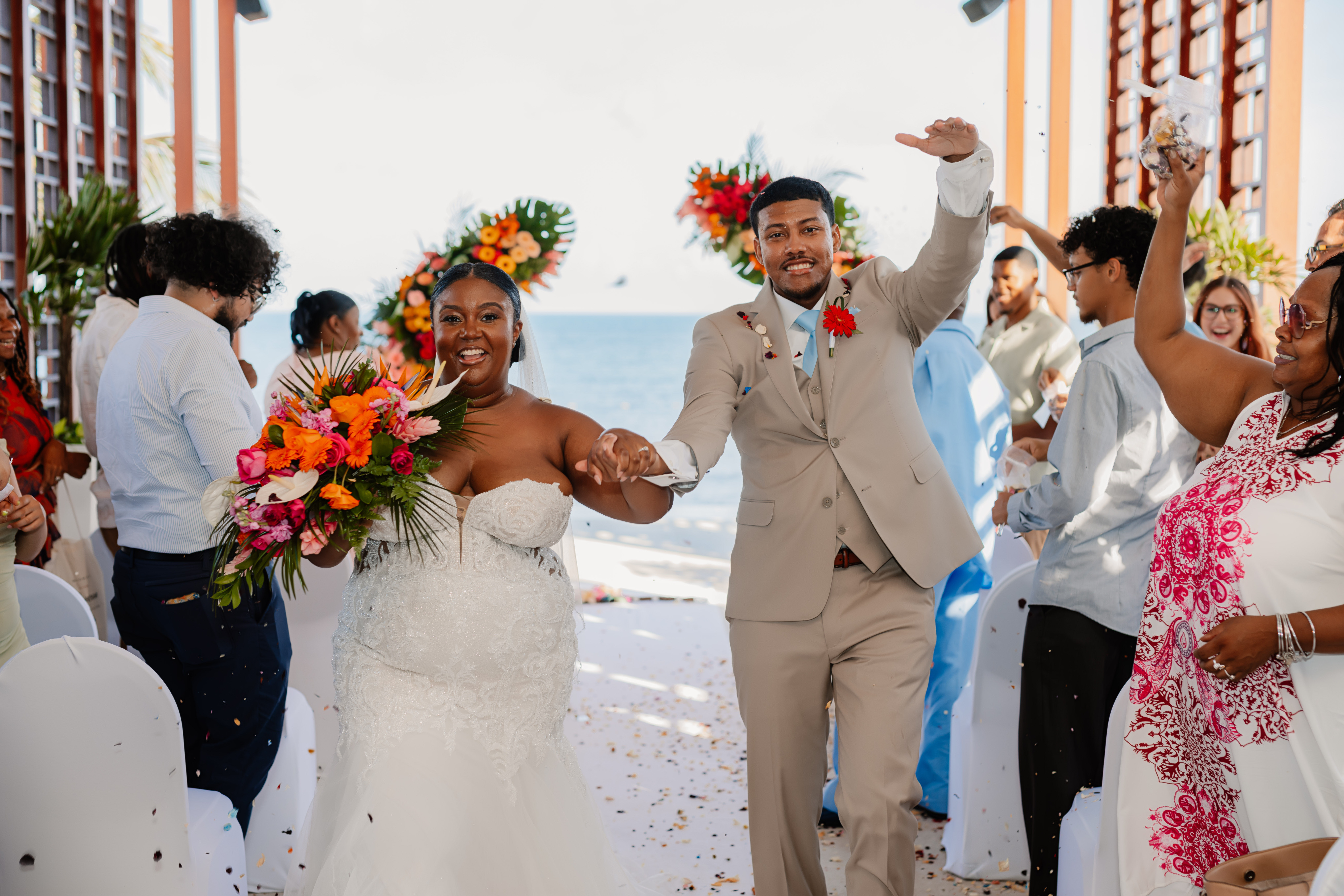 Jessie and Taylor celebrate as they walk down the aisle, smiling at their destination wedding on the beach.