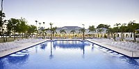 Large outdoor pool with white lounge chairs and palm trees, ideal for a destination wedding at Bahia Principe Grand Samana.