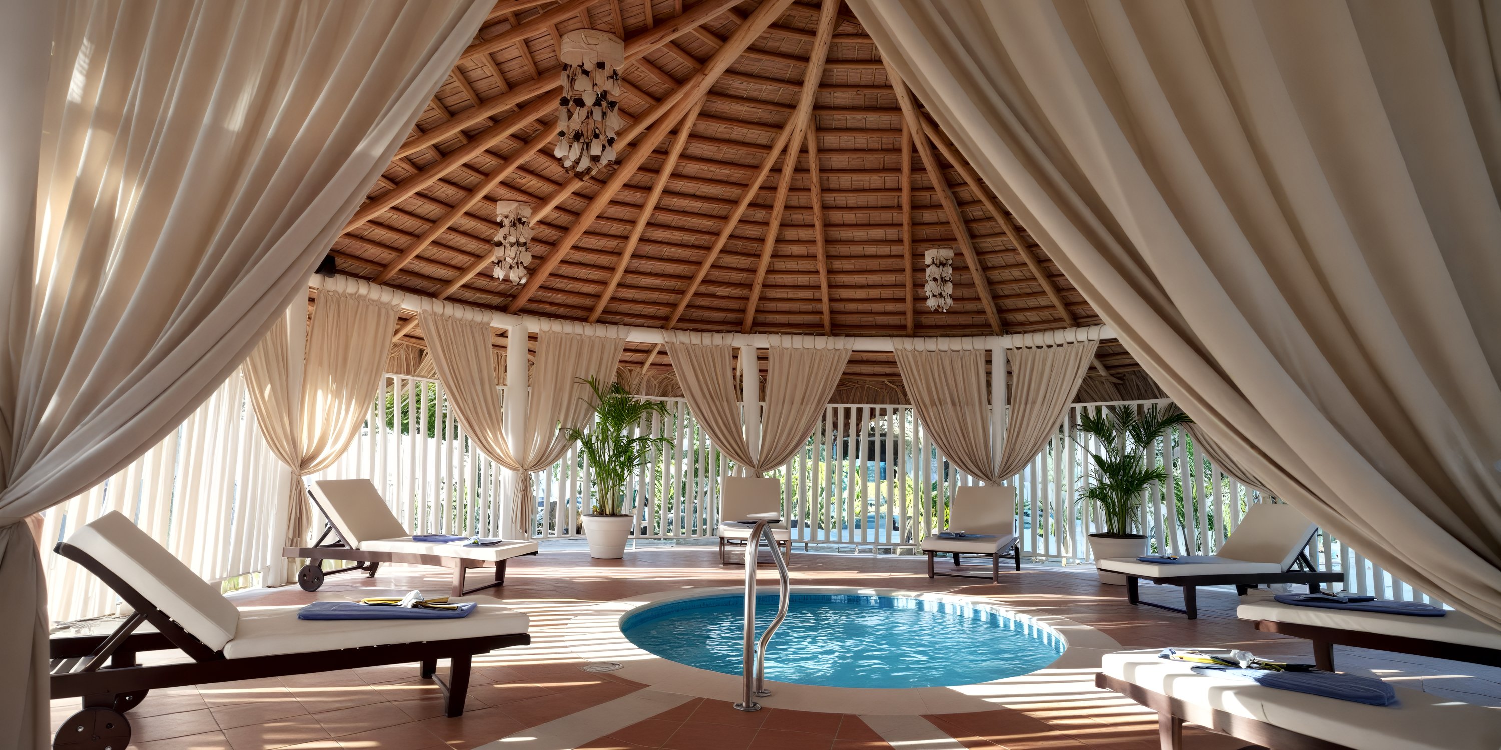 Round indoor pool at Bahia Principe Grand Samana, perfect for a destination wedding, with lounge chairs and draped curtains.