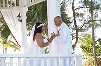 Richard and Keily stand face to face in wedding attire on a white gazebo at their destination wedding.