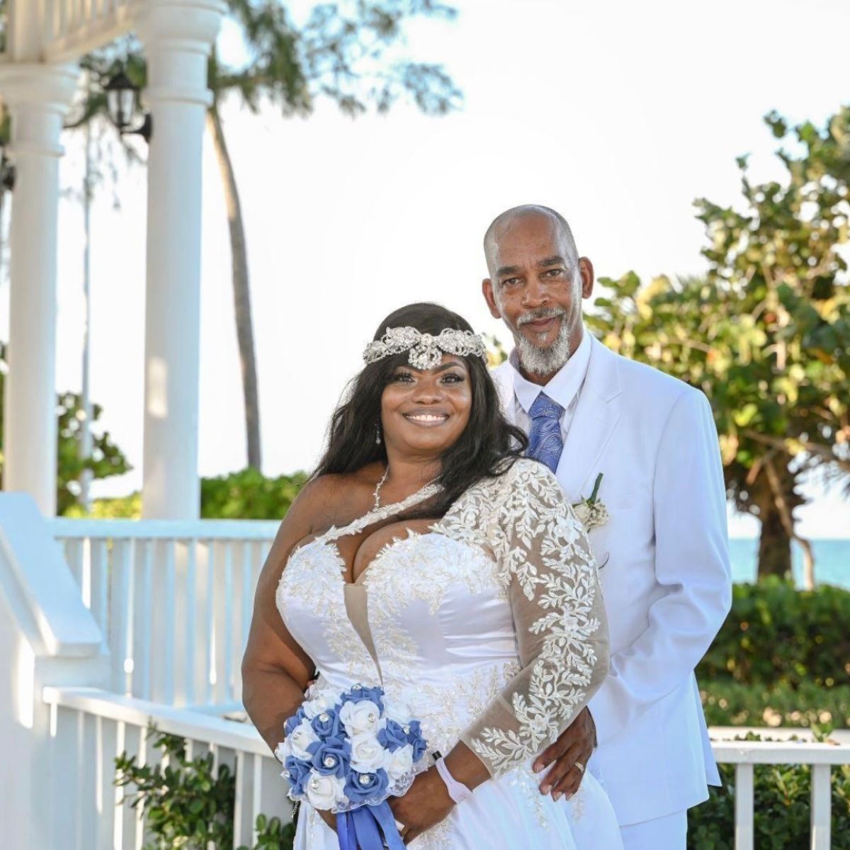 Richard and Keily (Copy) pose together in white outdoors at a destination wedding venue.