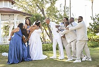 At a destination wedding, the bridal party playfully pulls Richard and Keily apart near an outdoor gazebo.