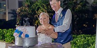 A bride and groom cut their cake together during a destination wedding at an outdoor reception.