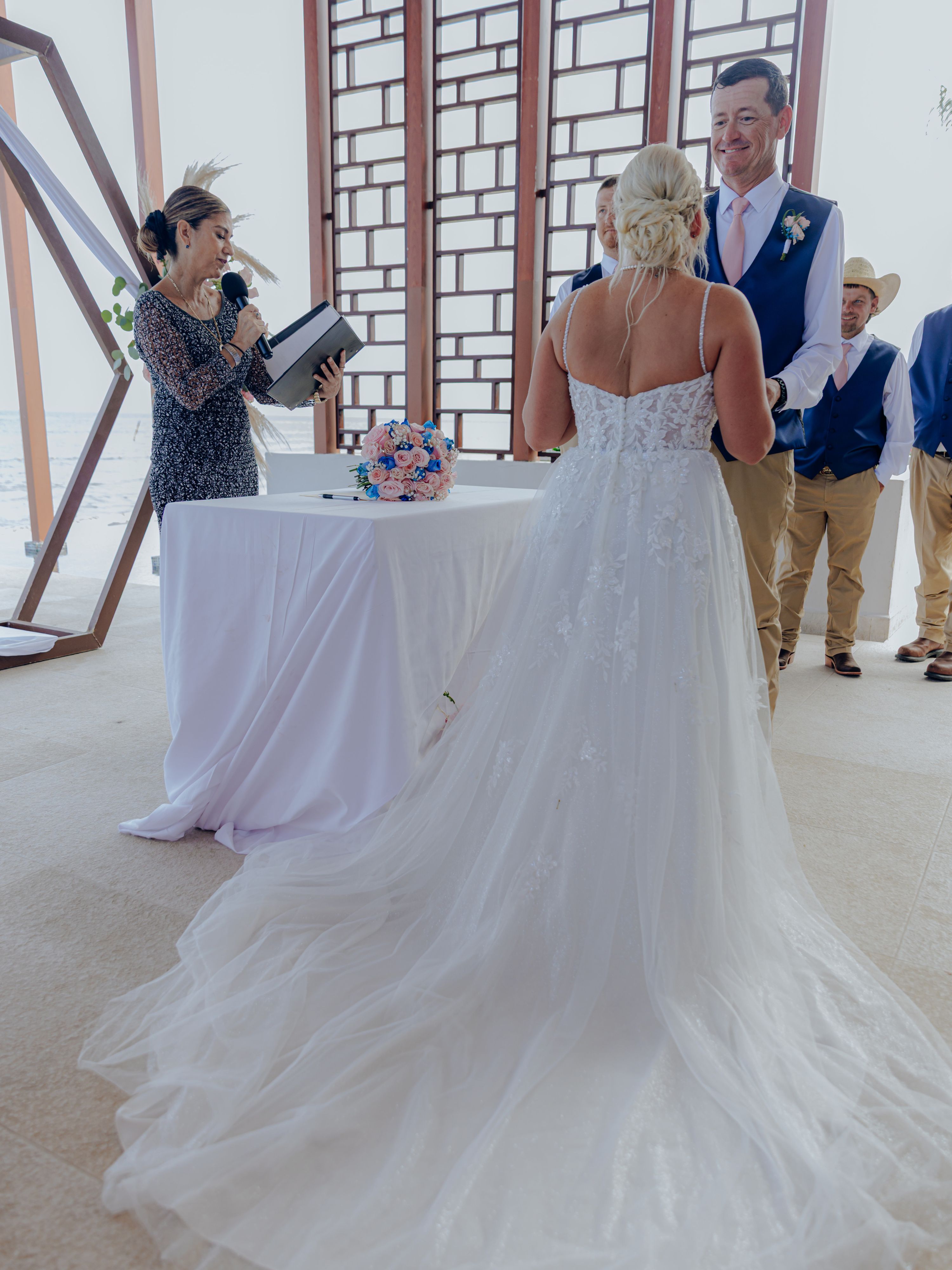 Bride and groom stand before the officiant at a modern indoor destination wedding ceremony.