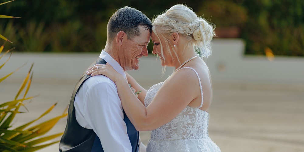 Bride and groom embrace and smile outdoors during their destination wedding, radiating happiness.
