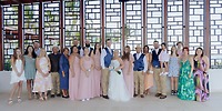 A destination wedding group poses inside before tall windows with striking geometric frames.