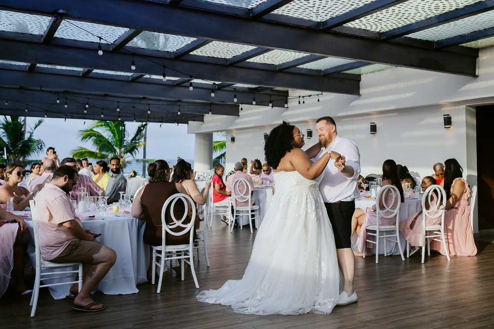 Alicia and Brian share their first dance as newlyweds at their wedding, surrounded by seated guests.