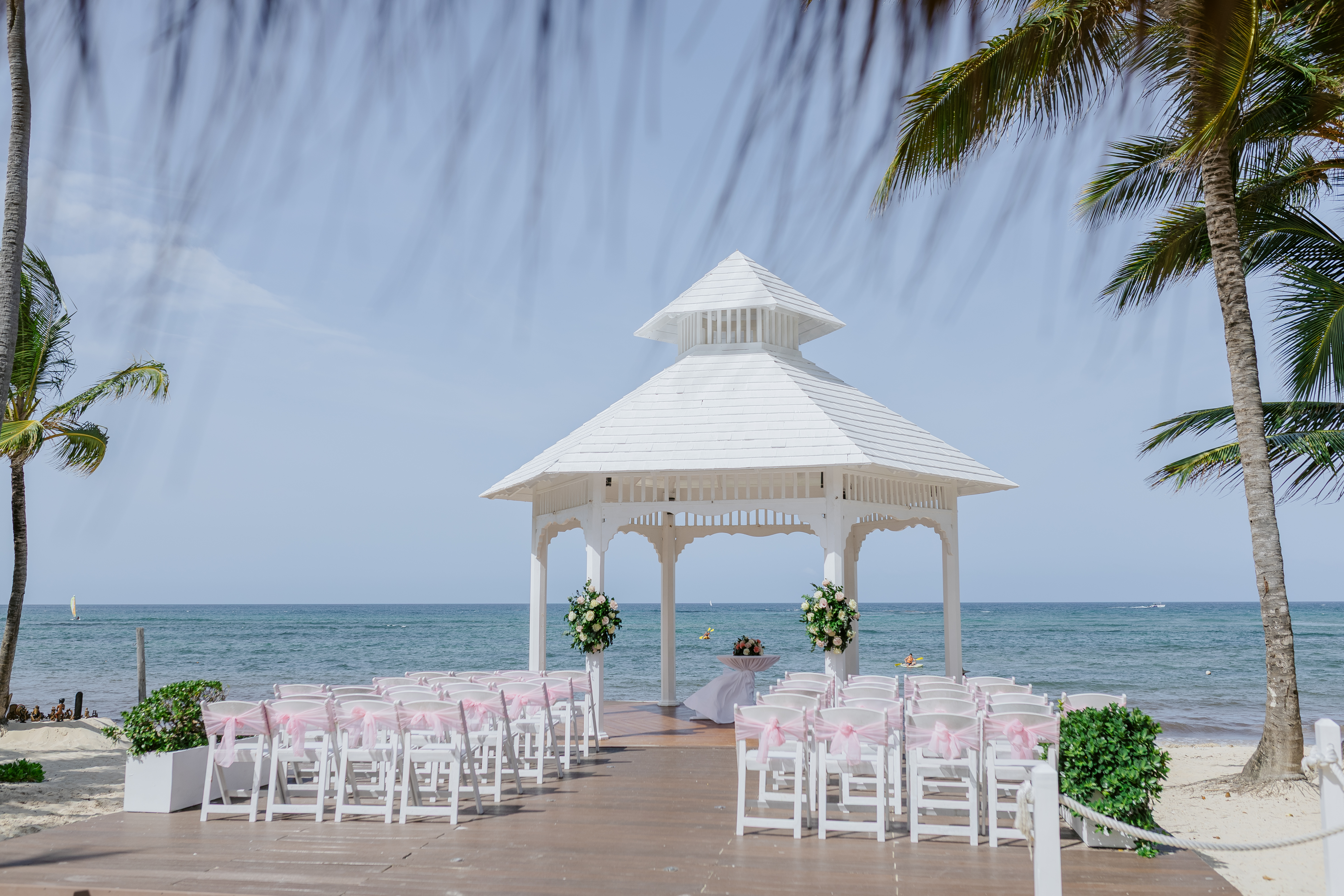 Destination wedding setup for Alicia and Brian: white gazebo on the beach, chairs lined up in rows.