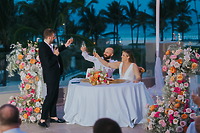 A man raises a toast to Billi and Trevor at their decorated outdoor destination wedding at dusk.