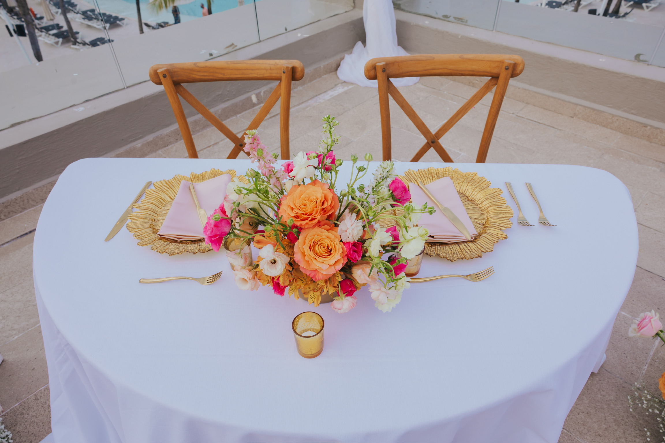 Billi and Trevor's destination wedding table for two with floral centerpiece, gold utensils, terrace view.