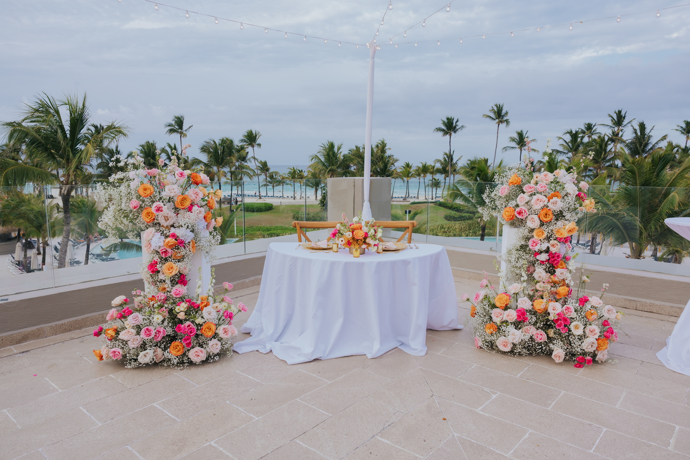The Billi and Trevor wedding table features florals on a terrace with palm and ocean views, perfect for a destination wedding.