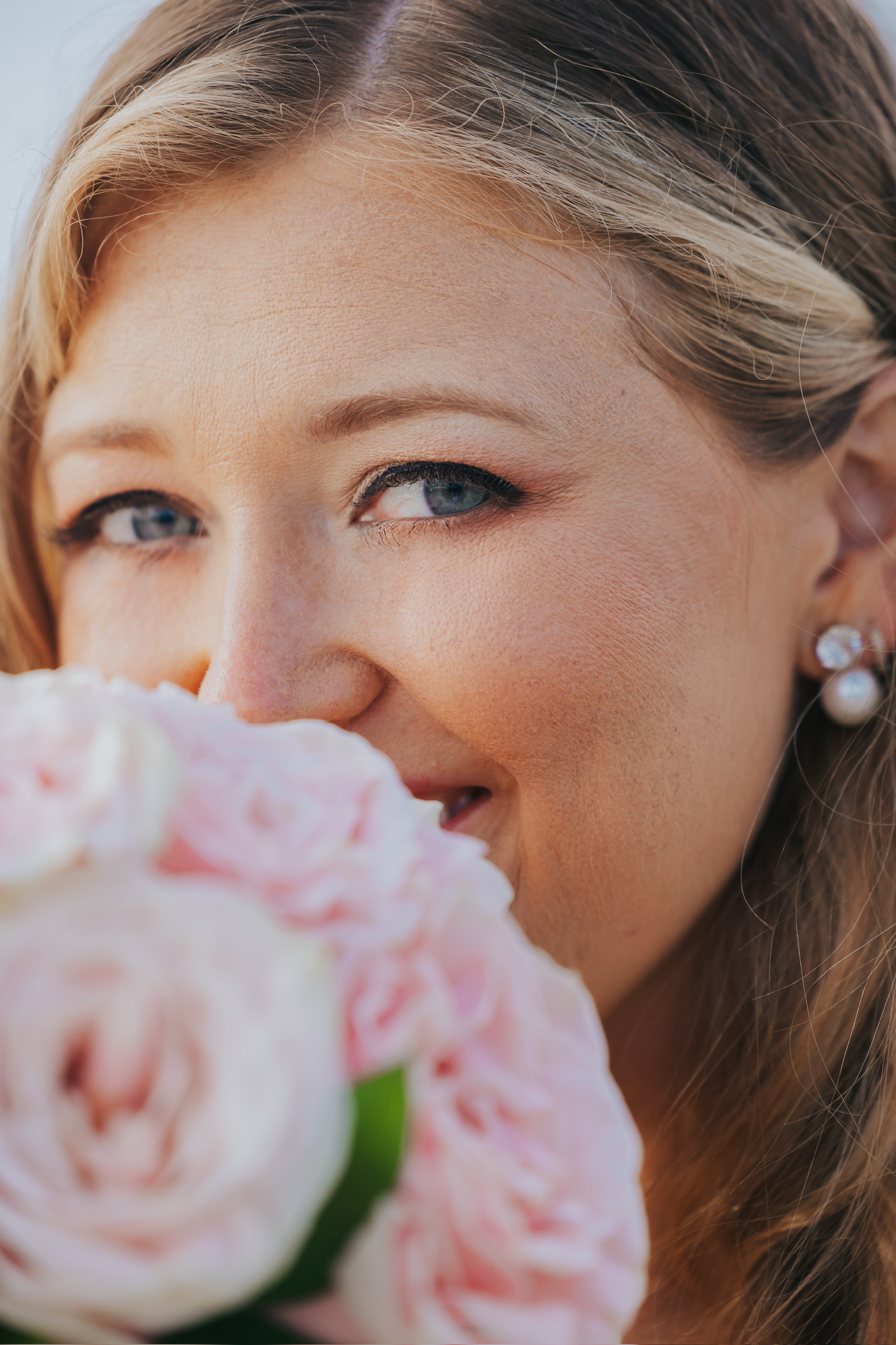 Woman with blue eyes holding a Billi and Trevor bouquet, smiling slightly at her destination wedding.