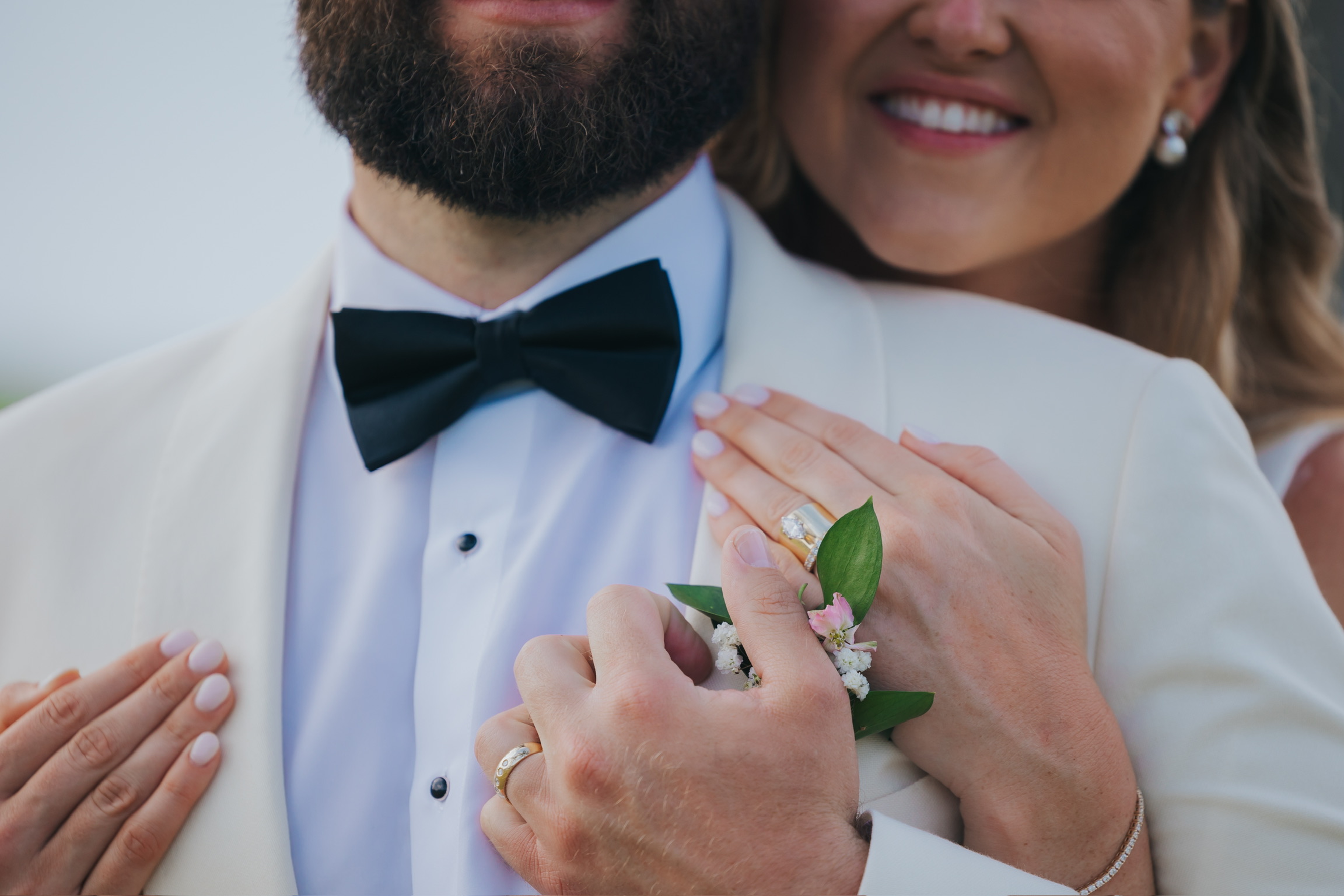 Billi and Trevor embrace in formalwear at their destination wedding, displaying rings and boutonniere.