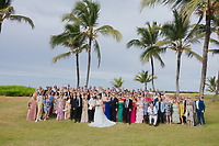A destination wedding group outdoors under palm trees, with Billi and Trevor in the center.
