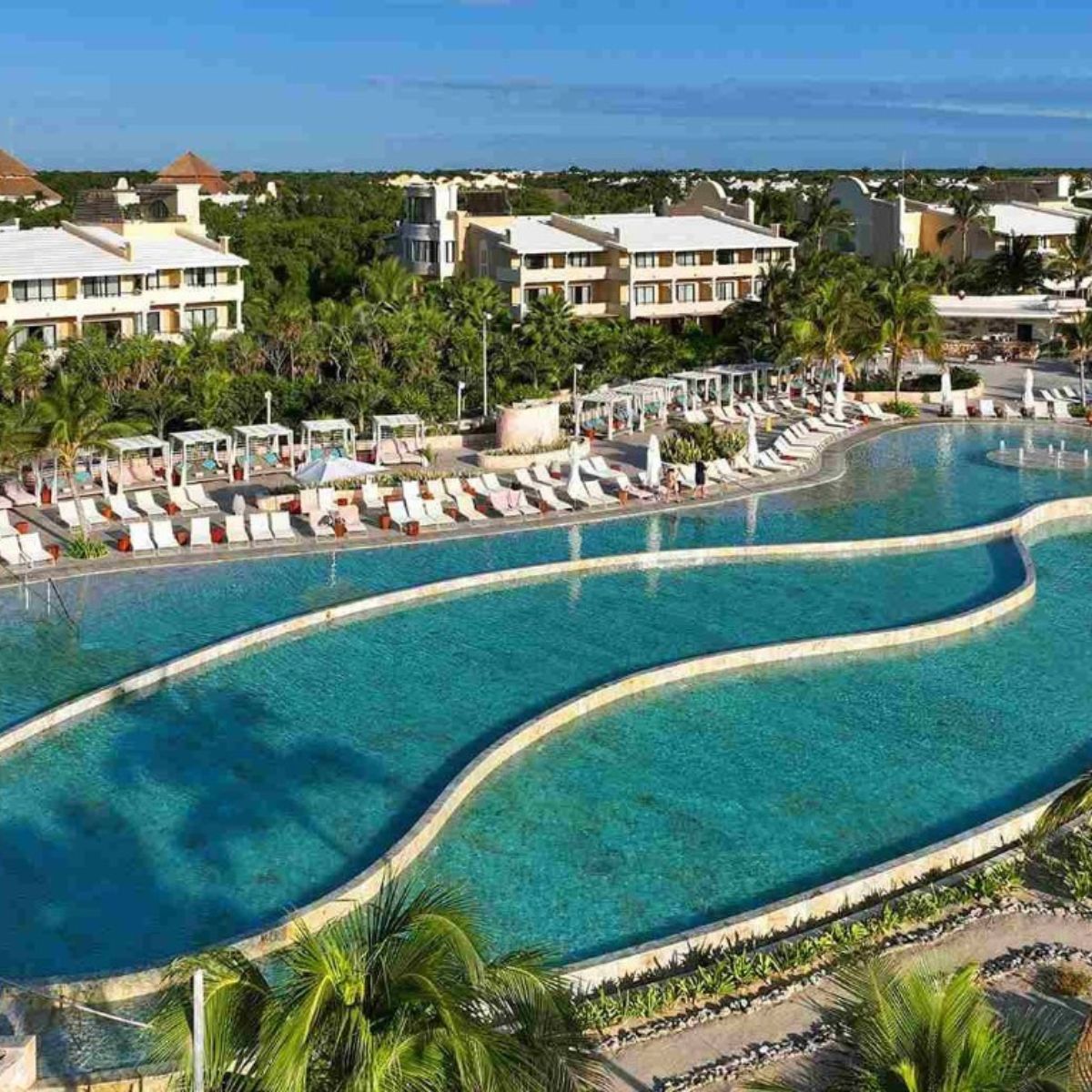 Spacious resort pool with lounge chairs and palm trees, an ideal setting for a destination wedding.