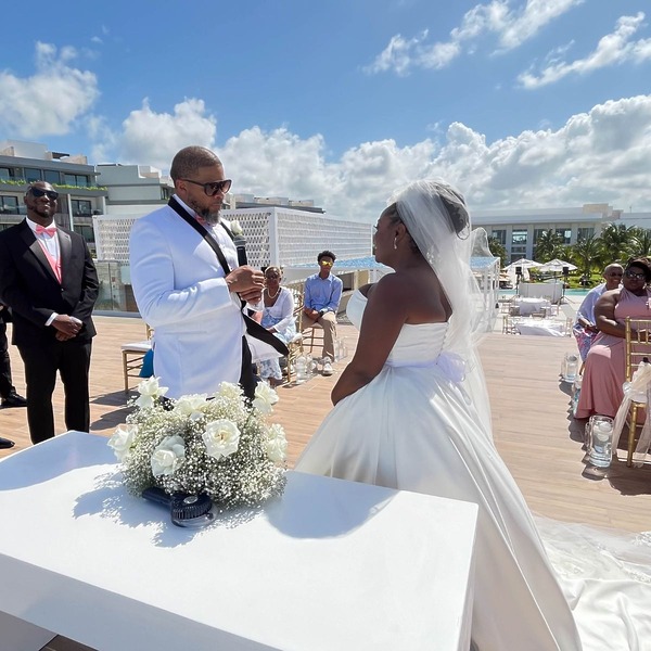 Iyana and Marcello (Copy) exchange vows during a sunny destination wedding ceremony outdoors.