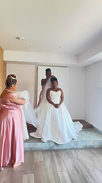At a destination wedding, four women assist a bride in her white gown with adjusting her veil.