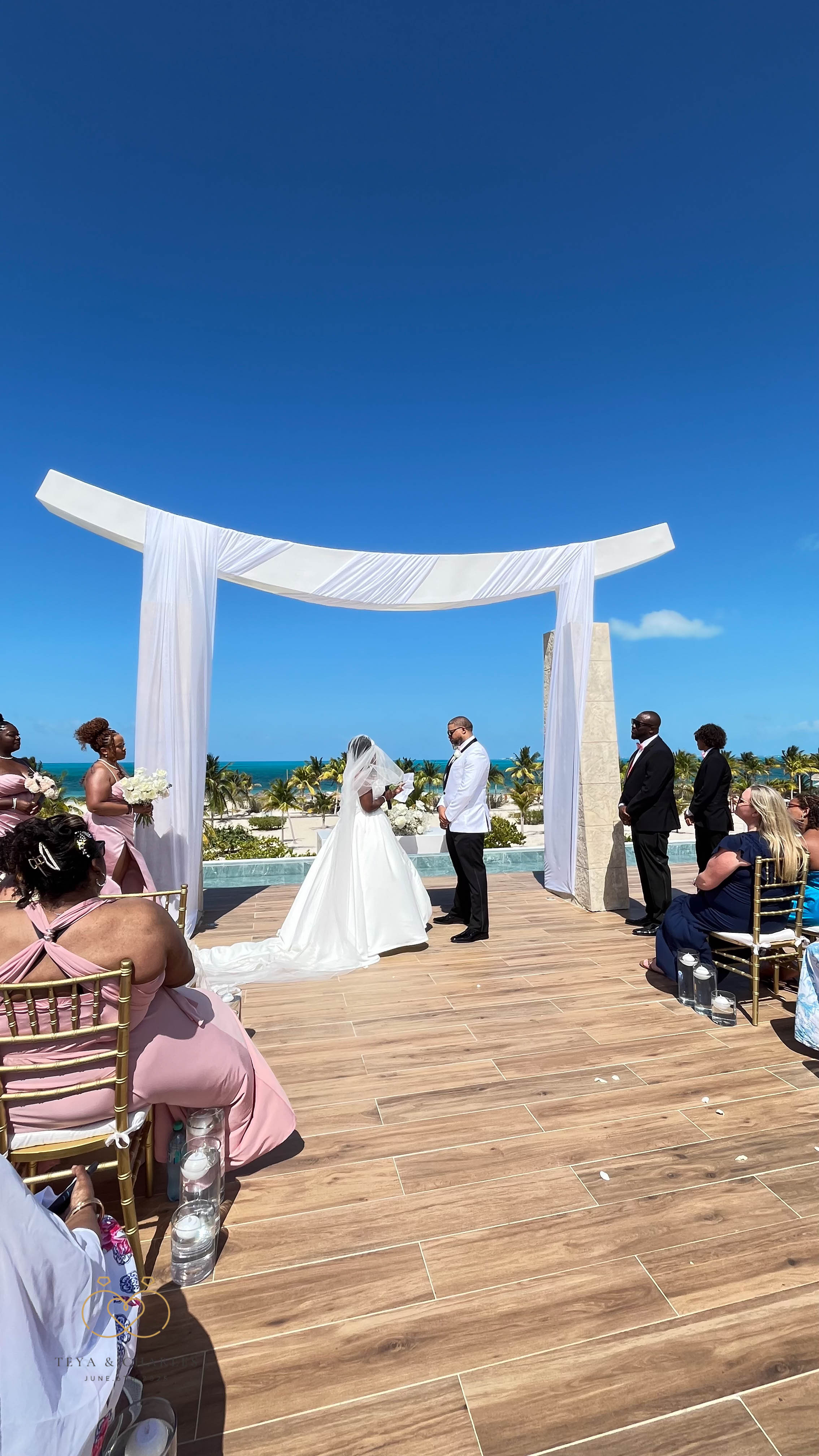 Iyana and Marcello stand beneath an arch at their destination wedding by the oceanfront.