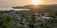 Wyndham Alltra Punta Cana: A dream destination wedding resort with palm trees, hills, and sunset ocean views.