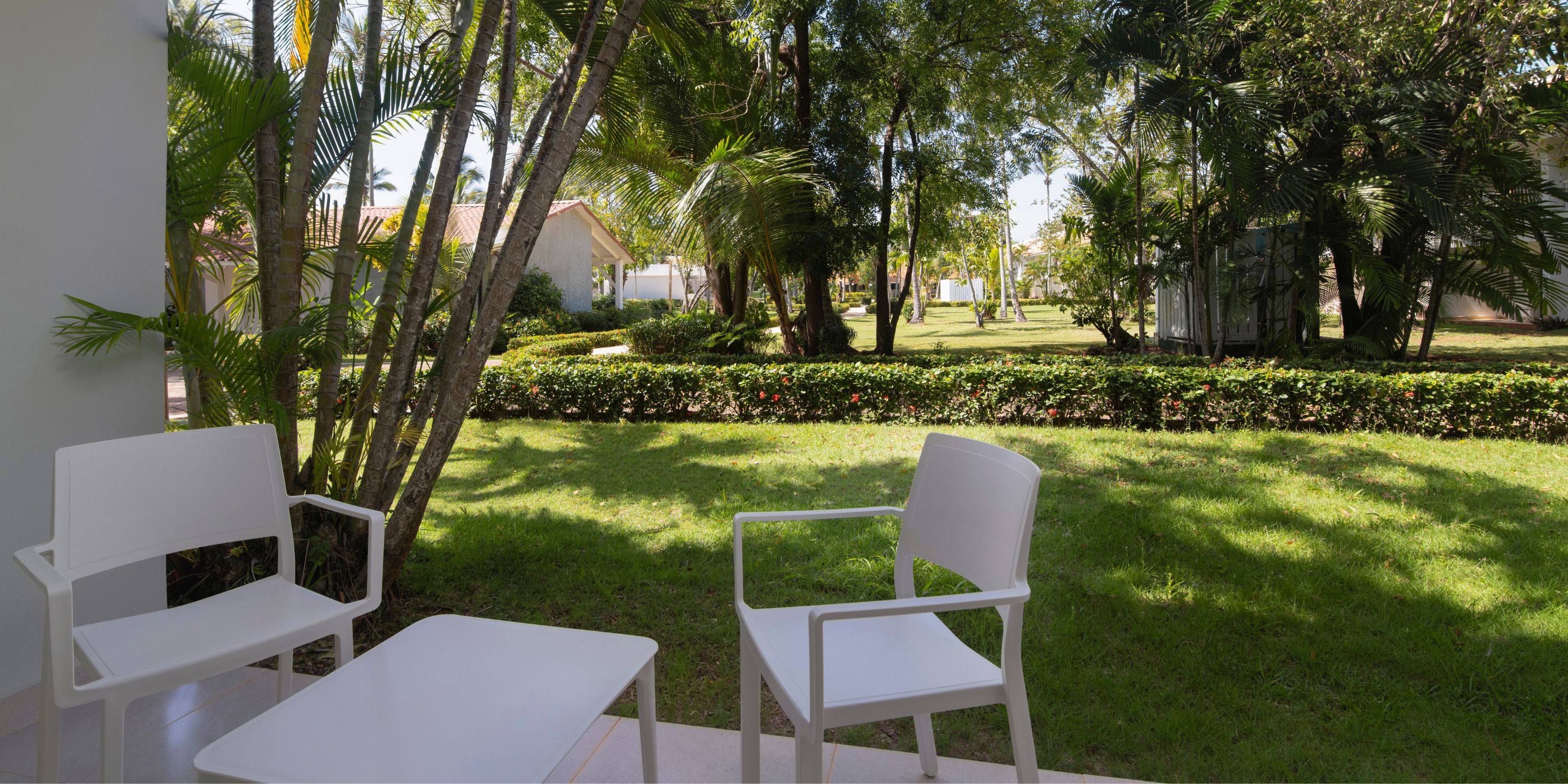 Wyndham Alltra Punta Cana patio set for a destination wedding, with two white chairs and grassy yard view.