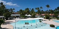 Wyndham Alltra Punta Cana’s spacious pool with white pergolas and palm trees, perfect for a wedding.