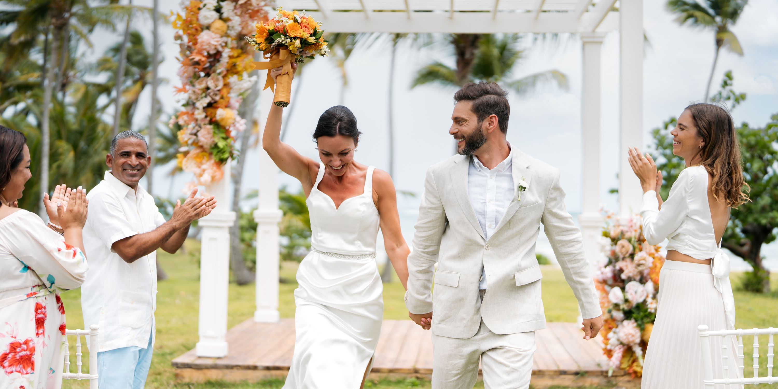 The newlyweds walk down the aisle at their destination wedding as guests clap outdoors in Punta Cana.