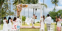 During a dreamy destination wedding at Wyndham Alltra Punta Cana, the groom lifts the bride under a floral arch.