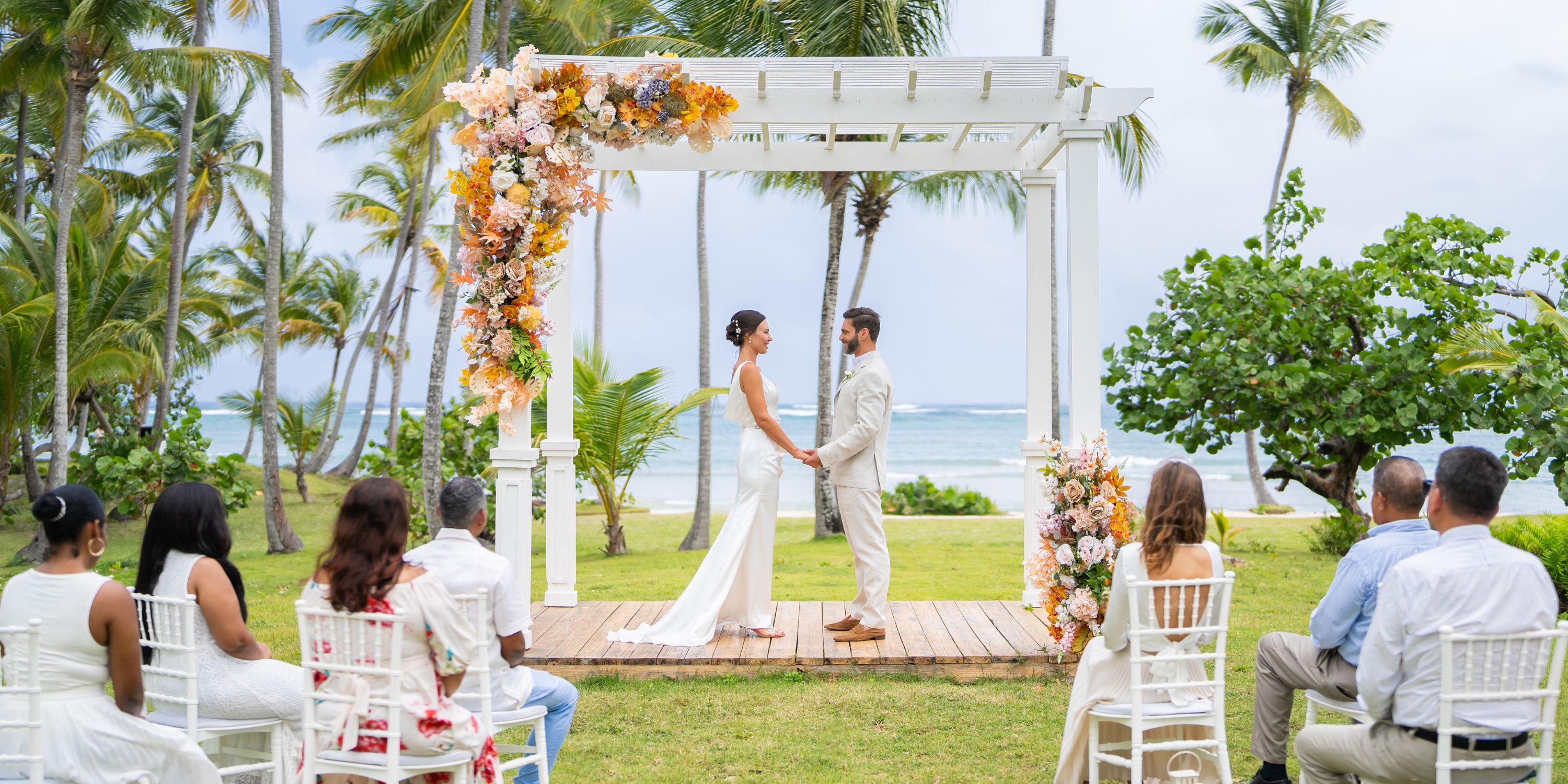 A couple exchanges vows beneath a floral arch at a destination wedding on Wyndham Alltra Punta Cana’s beach.