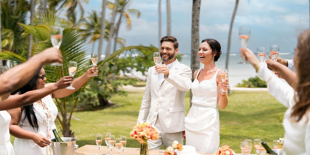 The newlyweds celebrate with a toast among guests at their destination wedding on Punta Cana beach.