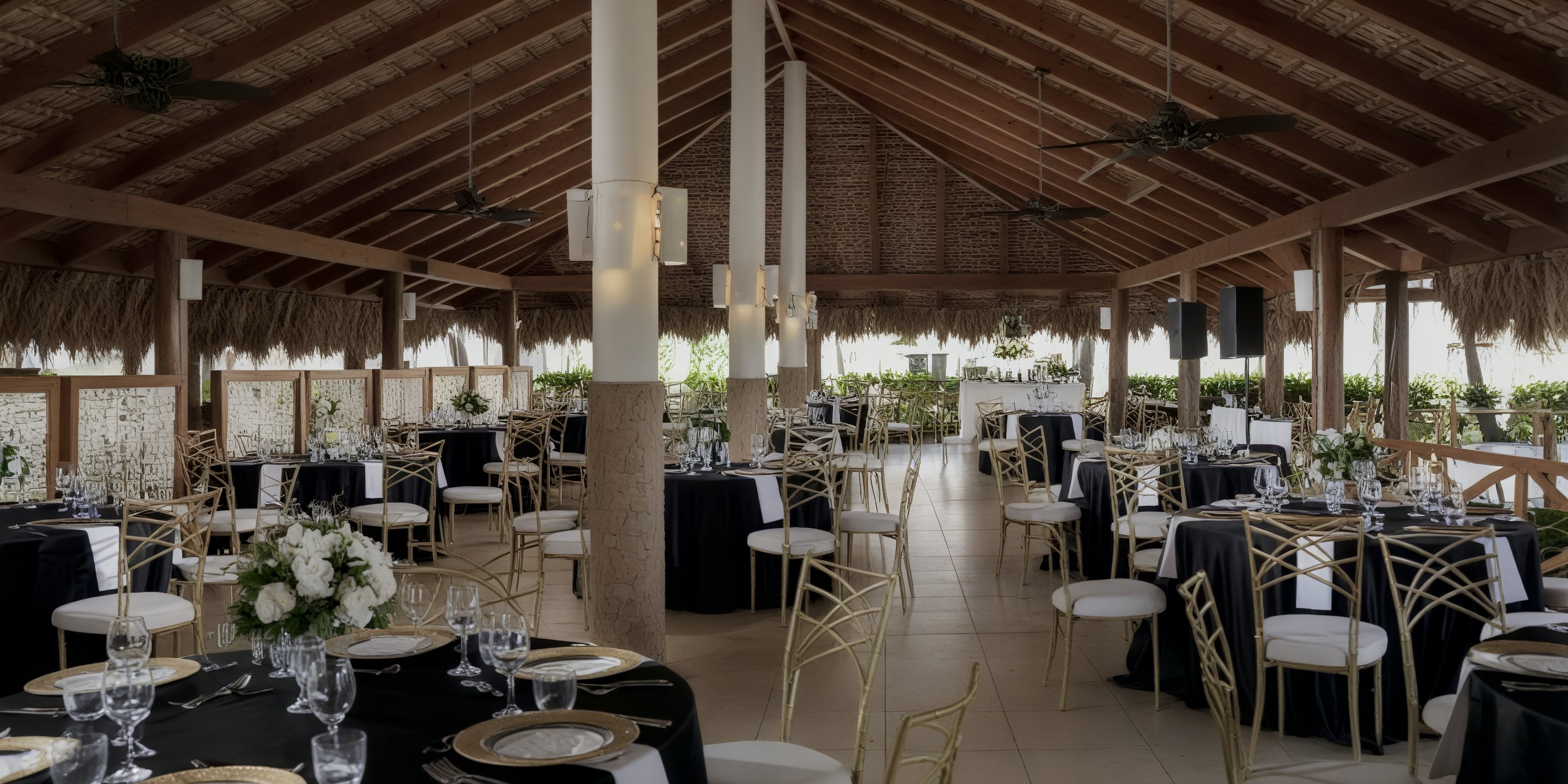 Elegant banquet hall prepared for a destination wedding, with round tables, black linens, and gold chairs.