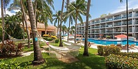 Hammocks by palm trees and pool near modern balconies, ideal for a dreamy destination wedding setting.