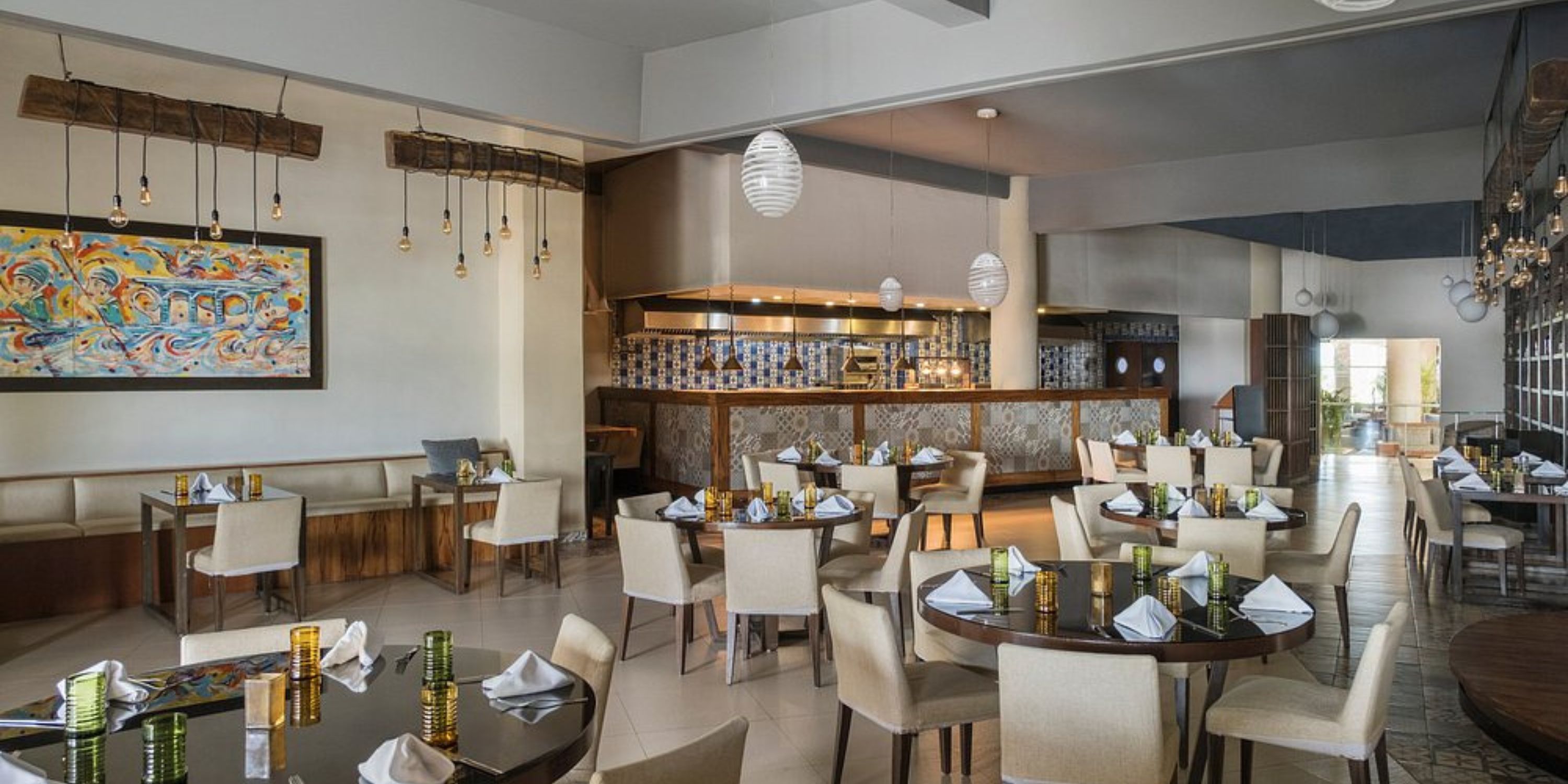 Chic interior at Iberostar Selection Riviera Cancun, perfect for a destination wedding, with round tables and an open kitchen.