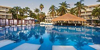 Outdoor pool with thatched-roof bar and lounge chairs, perfect for a destination wedding at Iberostar.