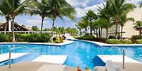 Iberostar Selection Riviera Cancun’s pool, palm trees, and bridge—ideal for a destination wedding.