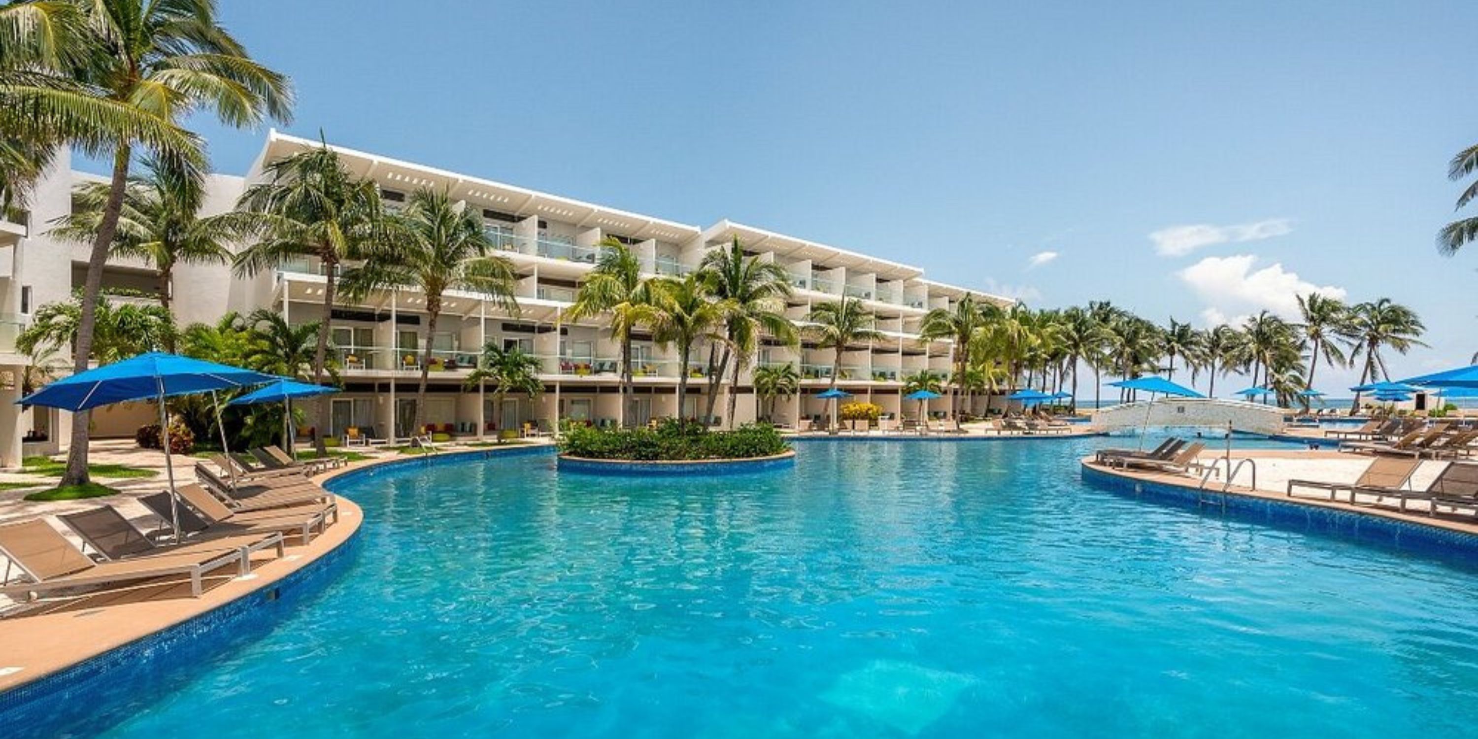 Iberostar Selection Riviera Cancun resort pool, ideal for a destination wedding, with lounge chairs, palm trees, and umbrellas.