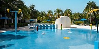 Iberostar Selection Riviera Cancun: splash pad with fountains, palms, chairs—perfect for a destination wedding.