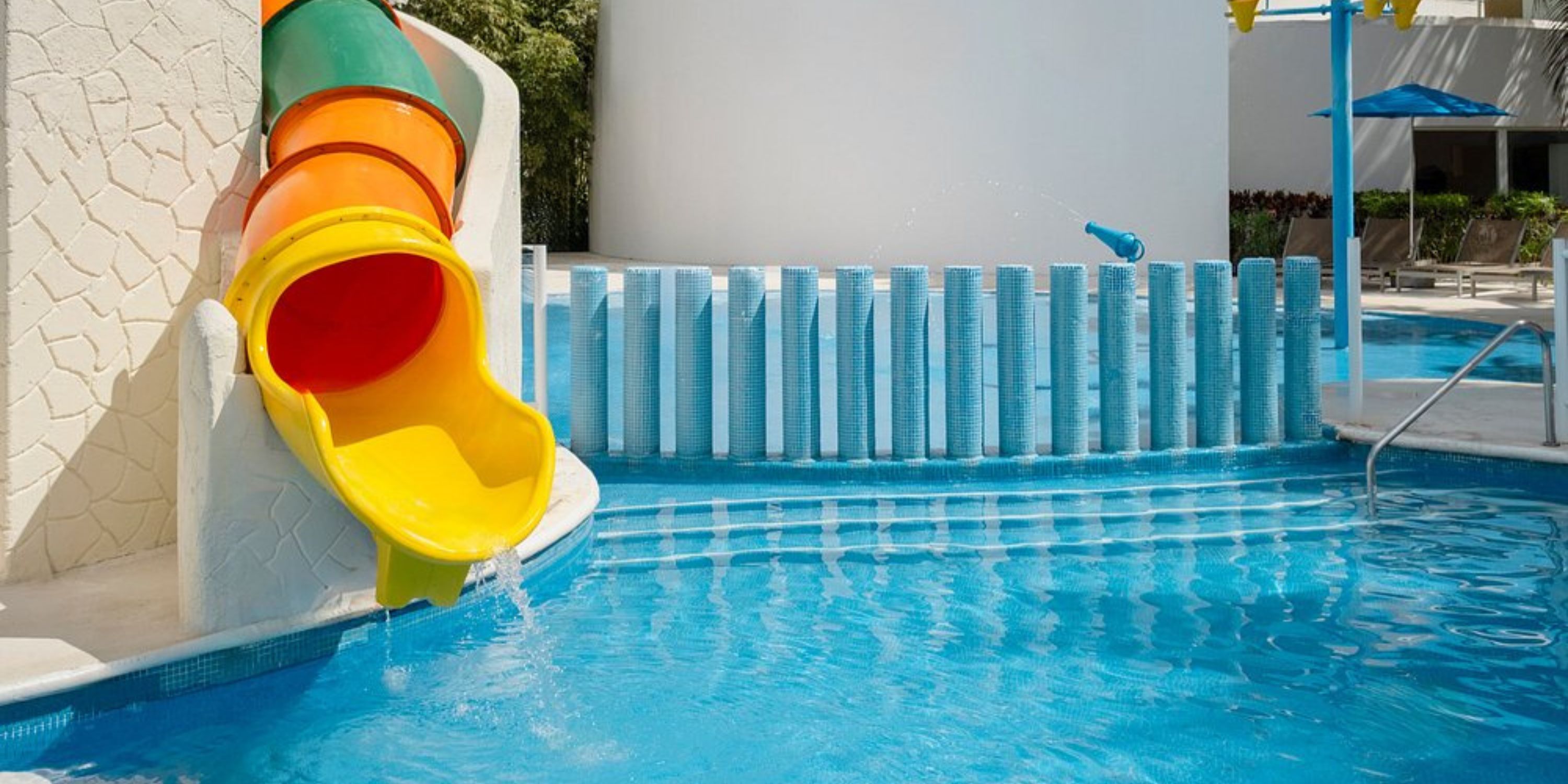 Colorful tube slide leads into a clear blue pool, perfect for a fun destination wedding at Iberostar.