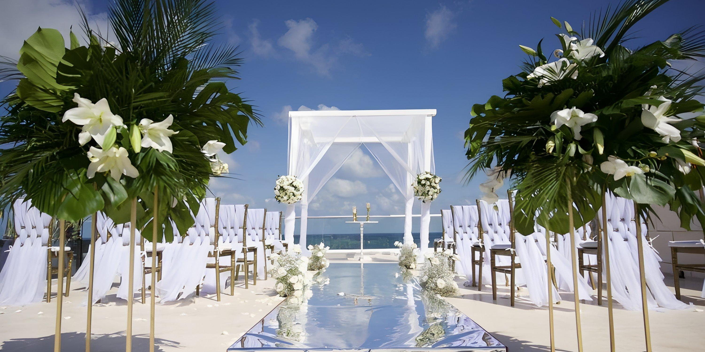 Elegant destination wedding setup by the sea at Iberostar Selection Riviera Cancun, with white decor and flowers.