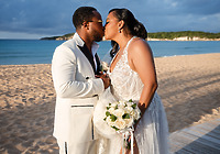 Leah and Ben share a kiss on a sandy beach, dressed in wedding attire at their destination wedding.