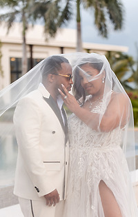 Leah and Ben stand outdoors under a veil in wedding attire at their destination wedding.