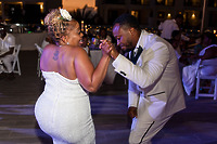 Leah and Ben dance outdoors in white outfits at a destination wedding during the evening.
