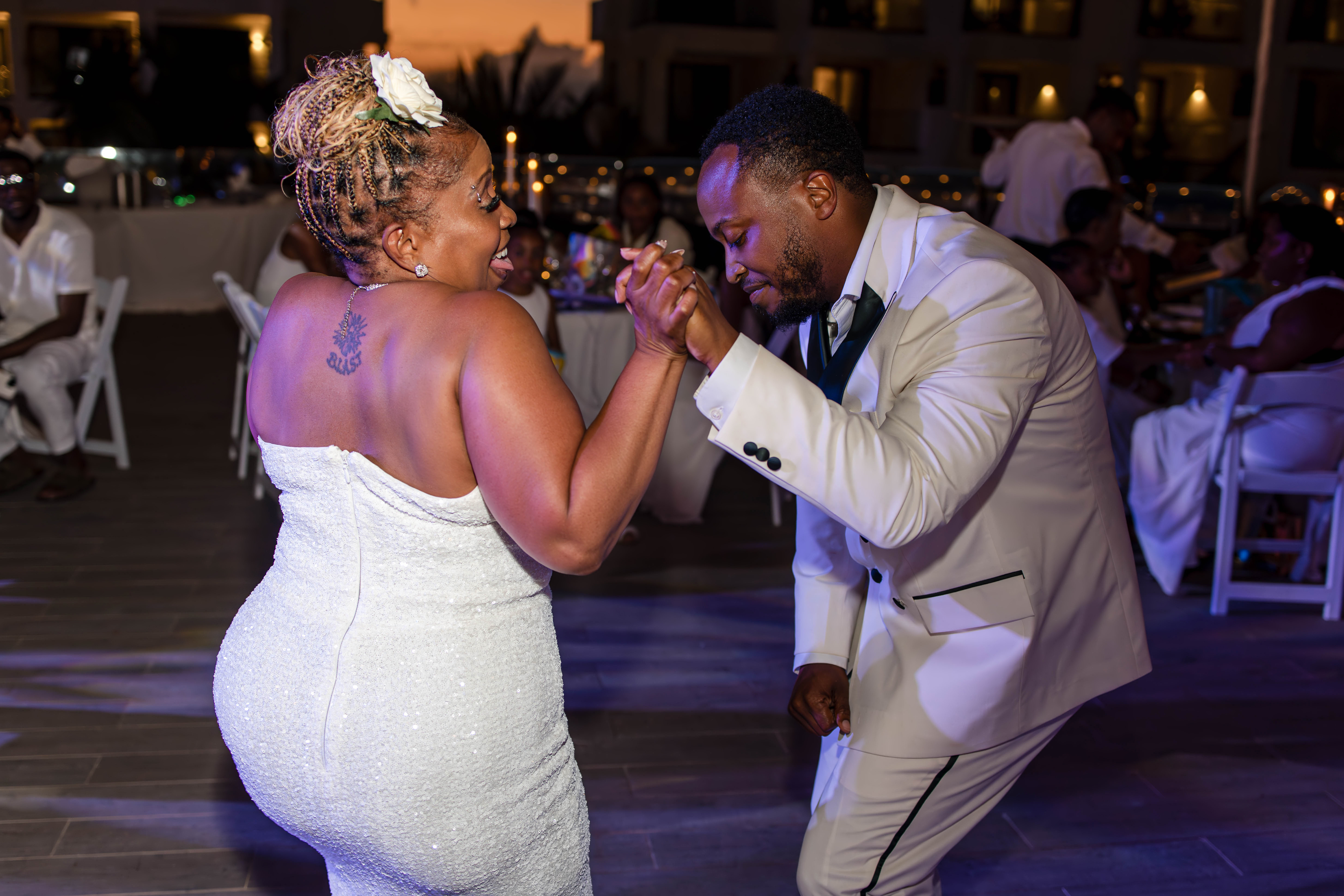 Leah and Ben dance outdoors in white outfits at a destination wedding during the evening.