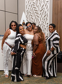Five women pose with drinks by a white wall at a destination wedding, including Leah and Ben.