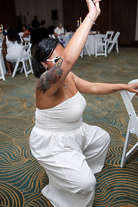 Person in a white outfit dancing with one arm raised at Leah and Ben's destination wedding indoors.