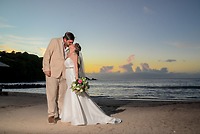 James and Brianna kiss on the beach at sunset, celebrating their destination wedding.