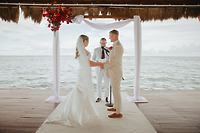 Kaitlyn and Chad face each other during a waterfront destination wedding ceremony outdoors.