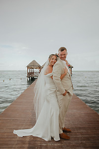 Kaitlyn and Chad stand back-to-back in wedding attire on a dock, perfect for a destination wedding.
