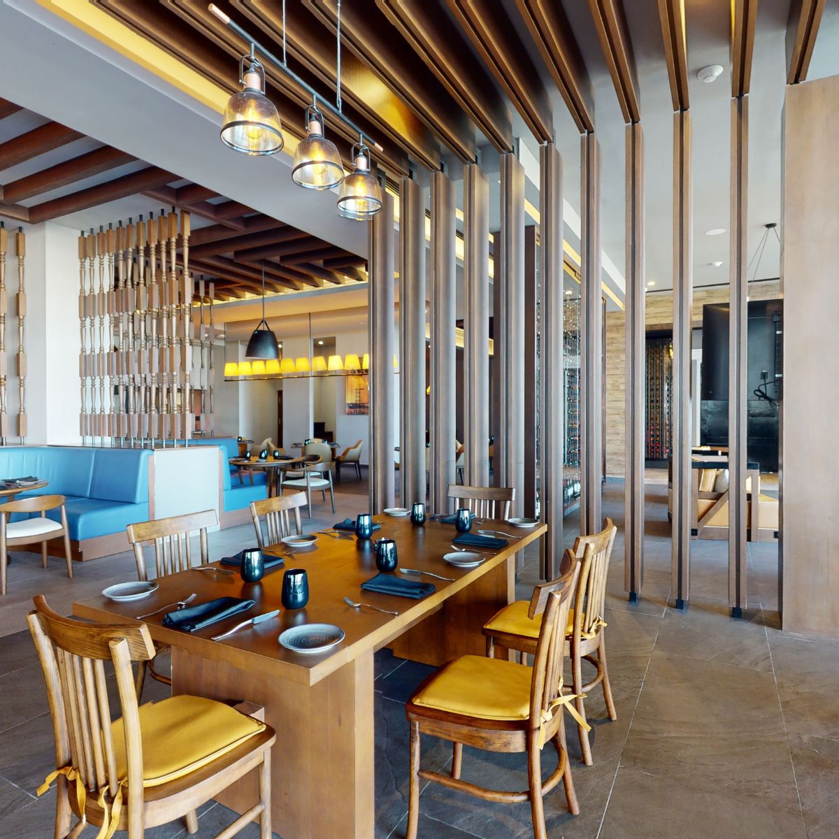 Modern restaurant interior with wooden furniture, set tables, and beams, ideal for a destination wedding.