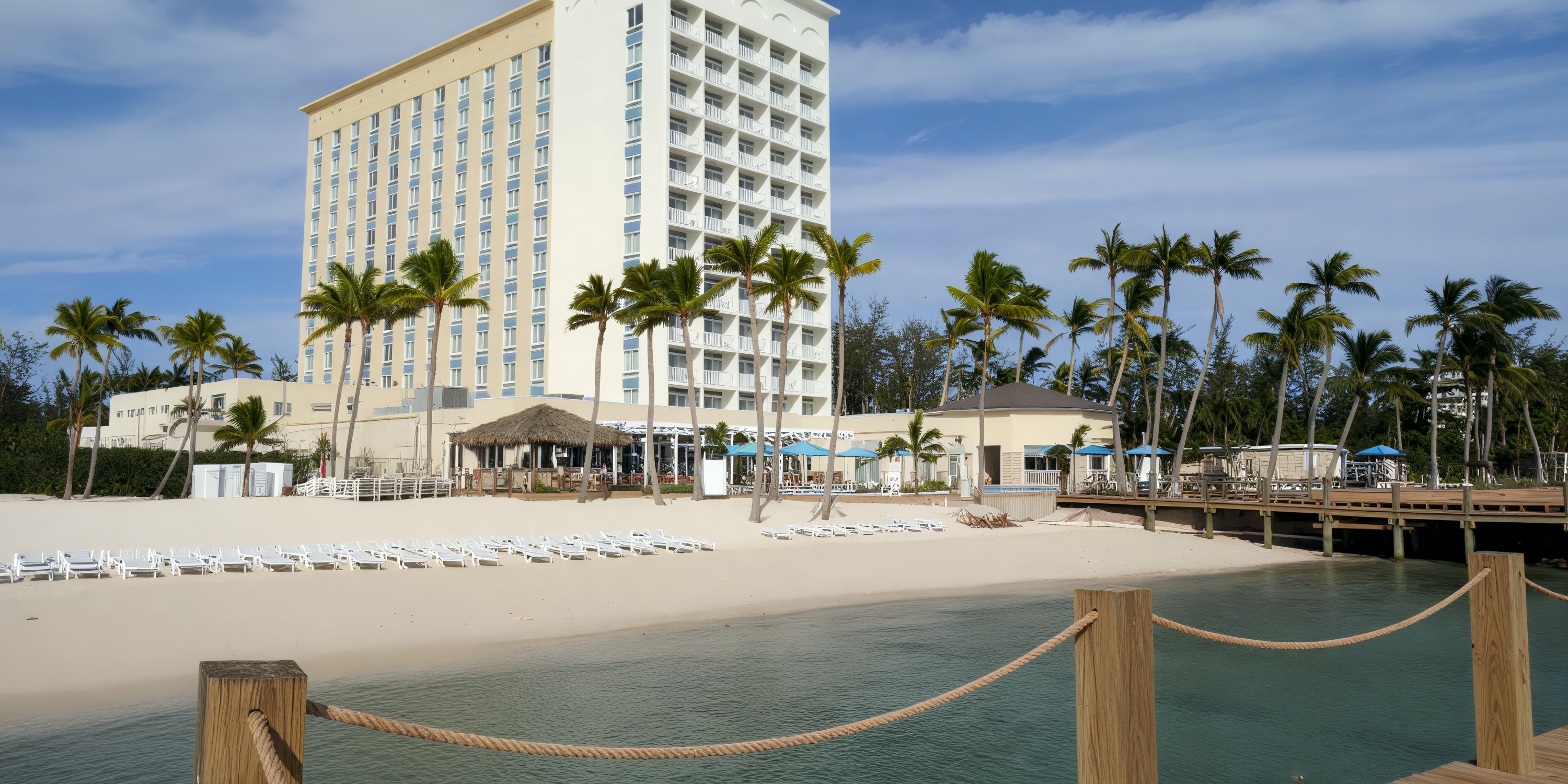 Warwick Paradise Island Bahamas: Ideal beachfront hotel for a destination wedding, with palms and lounge chairs.